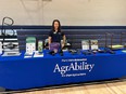 Abbie Spackman standing behind an AgrAbility for Pennsylvanians  booth in a gymnasium.