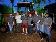 A TX AgrAbility client standing with 6 WTAMU engineering students and a dog in front of an International Harvester tractor.