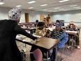 7 African American men and women in a room at long tables doing activities