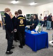 Abbie Spackman staffing the AgrAbility for Pennsylvanians booth with 4 FFA members in uniform talking with her