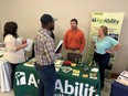 A young man and woman behind the SC AgrAbility booth table speaking with a Black man and woman in front of them