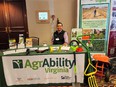 A man behind the AgrAbility Virginia table with an AgrAbility VA banner next to him & brochures & small AT on the table