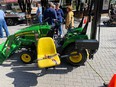 Small JD tractor with LifeLyfts lift on it and people standing behind it outside at NTW