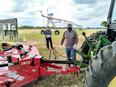 2 people looking at a tractor that's towing a bush-hog type mower