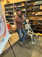 Man standing in a shop with a human skeleton seated in a chair next to him