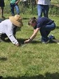 2 people squatting-kneeling on green grass while working with metal poles