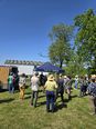 Crowd of people in a yard around a blue canopy bearing the words LUCE - ISFOP  