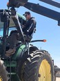 Man seated high on lift putting him into tractor cab