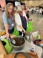 2 women looking at some ergonomic hand spades at a display table in a large conference room