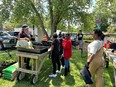 A group of African Americans outside next to some wheeled tables at Flanner Farms in Indianapolis