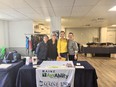 4 women standing together smiling at the camera with a Maine AgrAbility display table in front of them