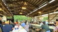 People sitting at long rows of tables watching a dinner theater in an open-sided barn