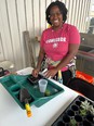 African American woman working with soil in small planters on a table