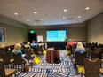 8 people listening to a presenter using a PowerPoint in a conference room.