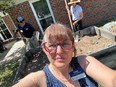 Selfie of Crystal Cook Marshall in foreground with 2 people working raised bed gardens in the background.