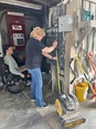 A woman standing in front of a man in a wheelchair and both of them looking at a tape measure the woman is using