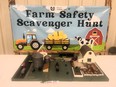 A toy farm on a table with a sign behind it reading FARM SAFETY SCAVENGER HUNT