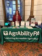 Young woman - Marci - standing behind AgrAbility PA display table