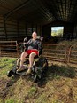 Woman - Teresa - in shorts and hoodie sitting on Trackchair in front of large farm pole barn