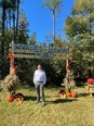 Roberto Franco standing under a sign ESTHER MANOR FARM with various squash and pumpkins decorating the base of the sign