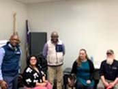 Mixed group of 3 men & 2 women in a room looking at the camera
