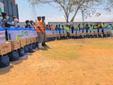 Ugandans standing in a long line behind a box and bucket in front of each person