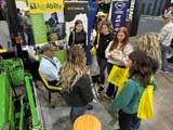 Carl Jenkins seated on the LifeLyfts tractor lift in the AgrAbility booth talking with a group of young ladies at the National Farm Machinery Show