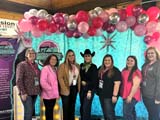 Eileen Legault and 6 other ladies standing under balloons at the Ladies Raising Livestock event