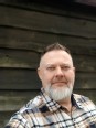 Portrait of Darin Chapman against a dark clapboard siding background