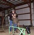A man showing a youth how to use a lariat to rope a plastic cow.