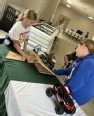 2 girls working at a table with toy tractors on different wood slopes to learn ag safety