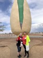 2 women standing in front of a 30 ft statue of a pistachio at Pistachio Land in NM