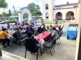 People sitting outside at long tables in a Spanish adobe style courtyard