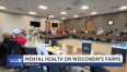 People seated at long tables in a square formation in a large conference room with printing that says MENTAL HEALTH ON WISCONSINS FARMS