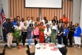 A racially mixed group of adults in 3 rows posing for a picture in a large room
