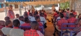 Picture of a class of African students under a canopy learning health and safety.