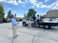 Marty Cotterman showing a young woman on a flat-bed truck lift how to operate the lift