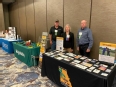 David Middleton - Karen Funkenbusch - and Kirk Funkenbusch standing behind AgrAbility booth at MO AgrAbility Show Me Strong Farm Families