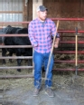Farmer with right forearm amputation holding a pitch fork in a farm building next to cattle stalls