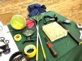 Various types of assistive technology laid out on a table with a green tablecloth