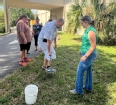 A small group of people outside taking soil samples in a yard.