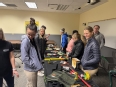 ISU OT students looking at small AT on tables in a classroom.