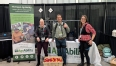 MI AgrAbility staff wearing exoskeletons at the Great Lakes Expo in front of the AgrAbility booth.