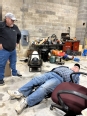Larry lying down on the AT creeper with another man looking on.