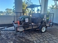 A Polaris Ranger on a trailer parked outside on a covered brick driveway.