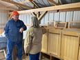 A man talking with Karen Funkenbusch next to some bee hives in a room.