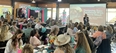 Shelli Rampold sharing a PowerPoint in front of a large room full of women seated at long tables.