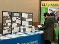 A woman looking at AgrAbility printed materials and a MO AgrAbility booth