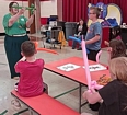 A woman showing balloon animals to children in a large room